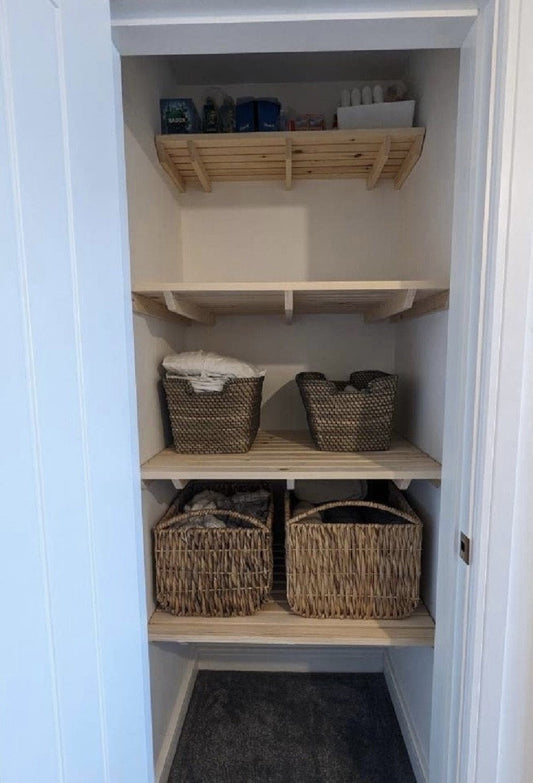 Organised airing cupboard with storage baskets on custom shelves